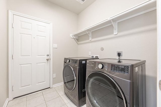 washroom featuring washing machine and dryer, baseboards, laundry area, and light tile patterned floors