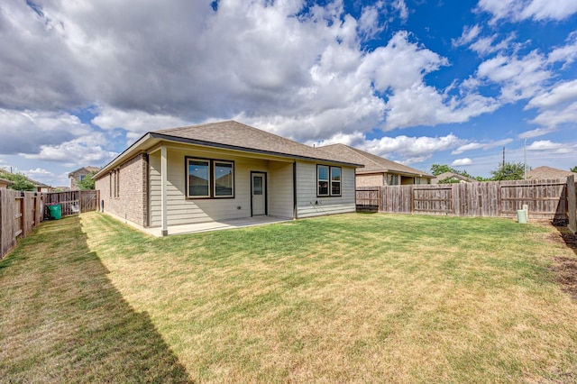 rear view of house featuring a yard, a patio area, and a fenced backyard