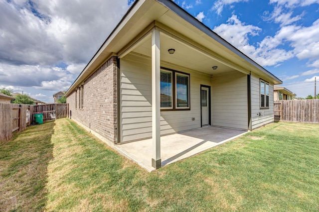 back of property featuring brick siding, a yard, a patio area, and a fenced backyard