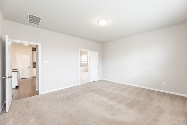 unfurnished bedroom with baseboards, ensuite bath, visible vents, and carpet flooring