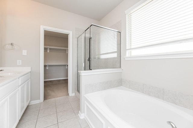 full bath featuring a spacious closet, a garden tub, tile patterned flooring, and a stall shower