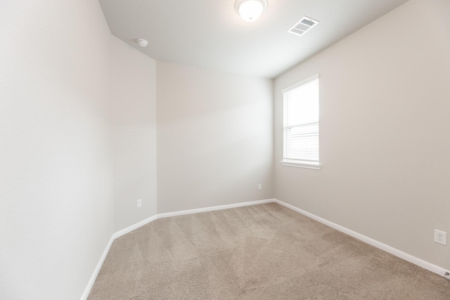 spare room featuring light colored carpet, baseboards, and visible vents