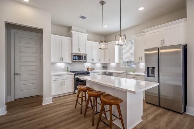 8411 Pech Landing Dr, Houston, TX 77055 - kitchen featuring appliances with stainless steel finishes, a sink, white cabinetry, dark wood-style floors, and a kitchen island