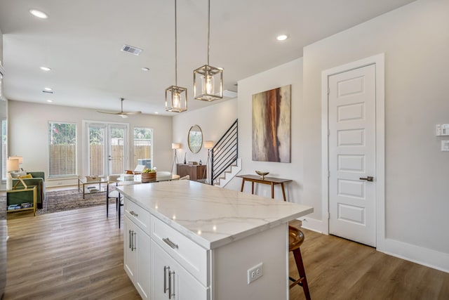 8411 Pech Landing Dr, Houston, TX 77055 - kitchen with a breakfast bar area, white cabinetry, wood finished floors, decorative light fixtures, and a kitchen island