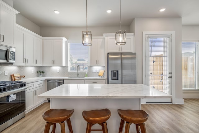 8411 Pech Landing Dr, Houston, TX 77055 - kitchen featuring appliances with stainless steel finishes, a sink, a breakfast bar area, light wood-style flooring, and backsplash