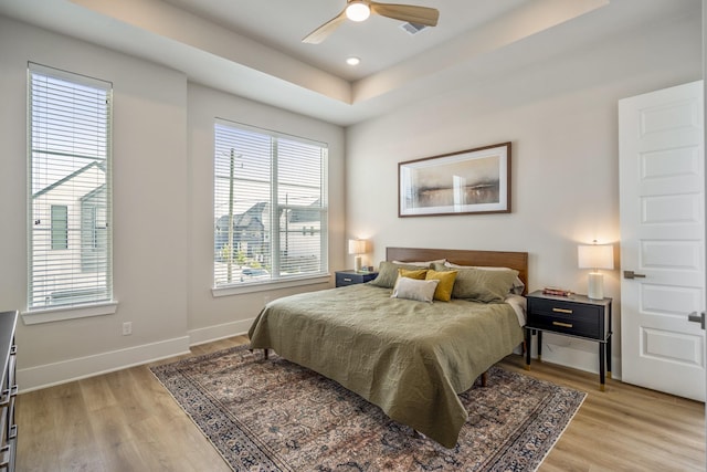8411 Pech Landing Dr, Houston, TX 77055 - bedroom with light wood-style floors, baseboards, a tray ceiling, and a ceiling fan