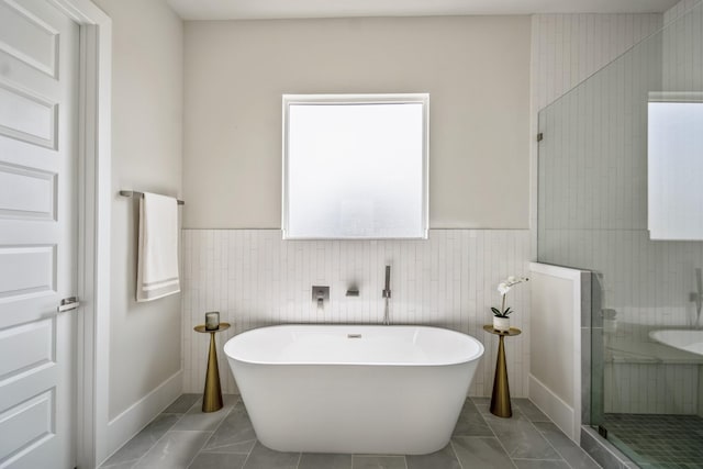 8411 Pech Landing Dr, Houston, TX 77055 - bathroom with a freestanding bath, tile walls, a stall shower, a wainscoted wall, and marble look tiles