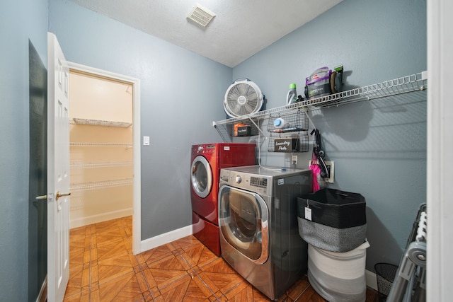 clothes washing area with baseboards, visible vents, washer and dryer, and laundry area