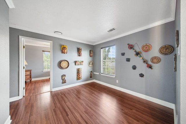 empty room with crown molding, plenty of natural light, visible vents, and dark wood finished floors