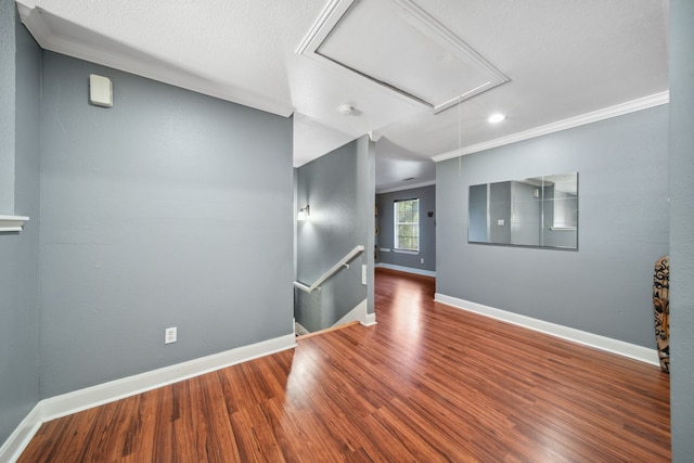 spare room with recessed lighting, wood finished floors, crown molding, baseboards, and attic access