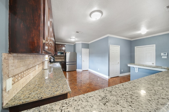 kitchen featuring baseboards, freestanding refrigerator, a textured ceiling, and tasteful backsplash
