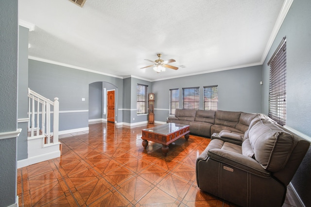 living area with a ceiling fan, arched walkways, crown molding, baseboards, and stairs