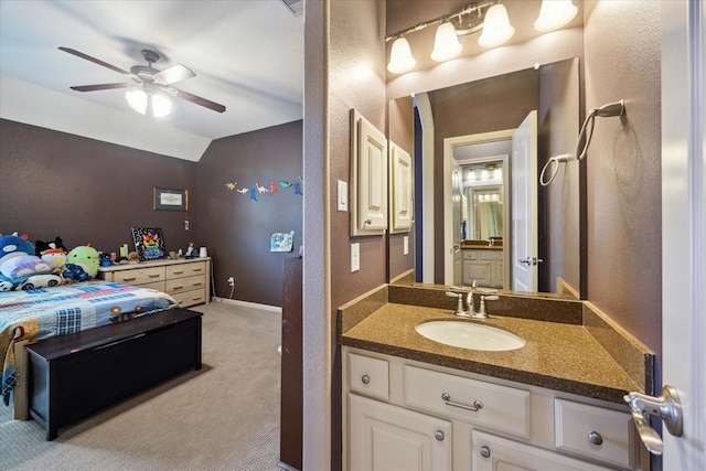 bathroom with a textured wall, a ceiling fan, vanity, and vaulted ceiling