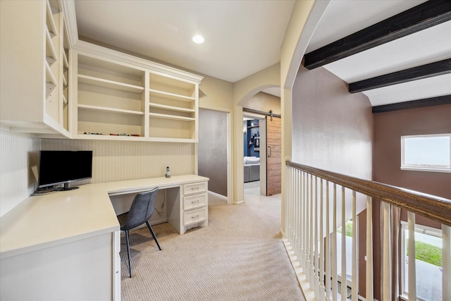 unfurnished office with built in study area, a barn door, light carpet, and a wealth of natural light