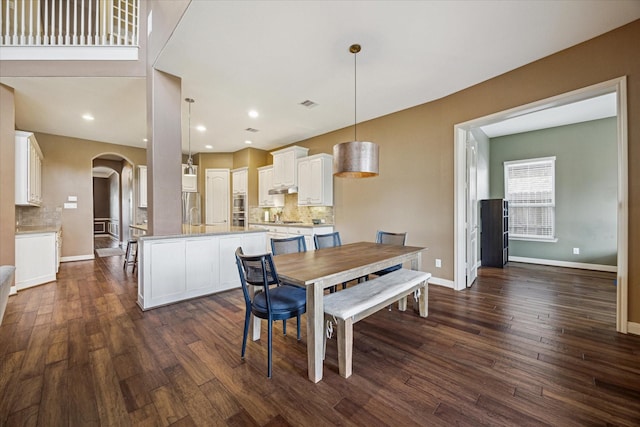 dining area featuring arched walkways, visible vents, dark wood-style floors, and baseboards