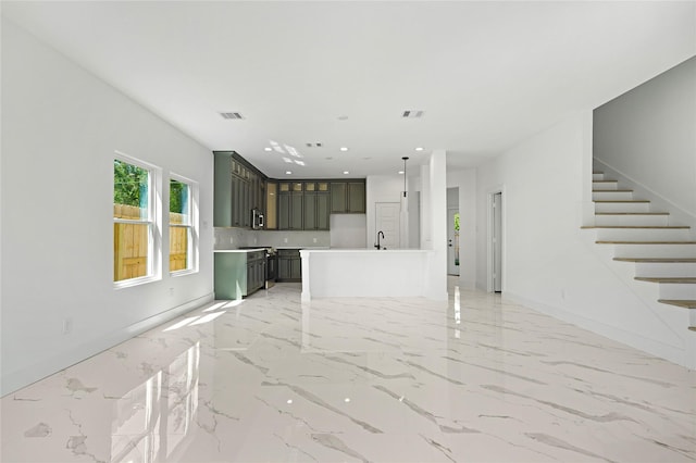 unfurnished living room featuring stairway, marble finish floor, a sink, and visible vents