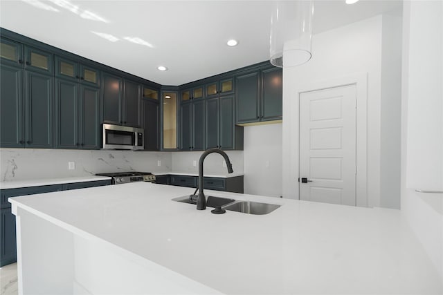 kitchen featuring a sink, recessed lighting, glass insert cabinets, light countertops, and appliances with stainless steel finishes