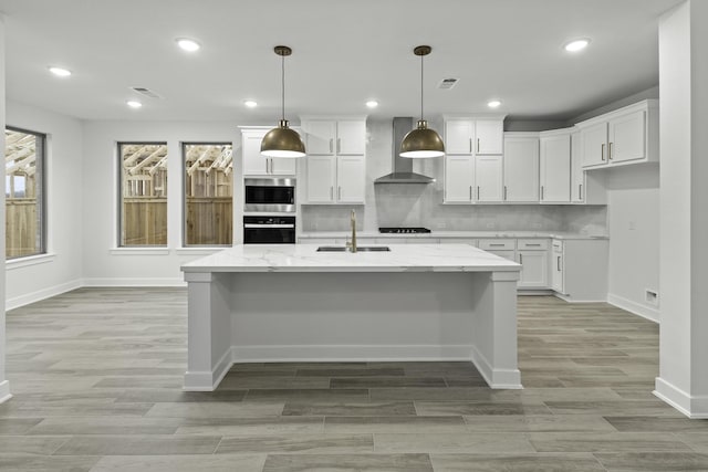 1159 Beals Creek St, Conroe, TX 77304 - kitchen featuring wall chimney exhaust hood, white cabinetry, light wood finished floors, light stone countertops, and recessed lighting