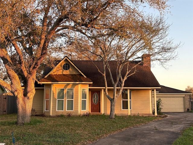 view of front of property with roof with shingles, driveway, fence, a garage, and a front yard