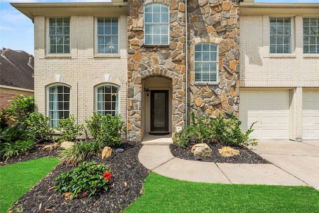 view of front of home featuring a garage, driveway, and stone siding