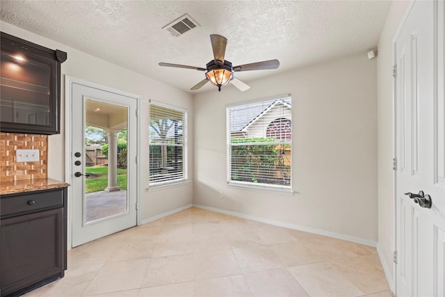 entryway featuring light tile patterned floors, baseboards, visible vents, a ceiling fan, and a textured ceiling