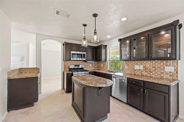 kitchen featuring light stone countertops, a sink, decorative backsplash, visible vents, and appliances with stainless steel finishes