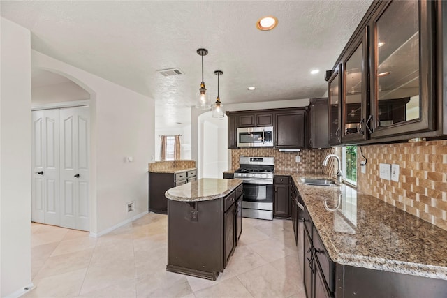 kitchen with a sink, stainless steel appliances, visible vents, arched walkways, and dark brown cabinets