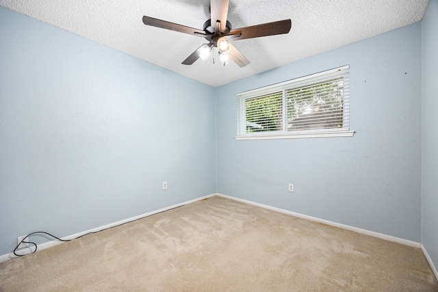 empty room featuring a textured ceiling, carpet flooring, baseboards, and a ceiling fan