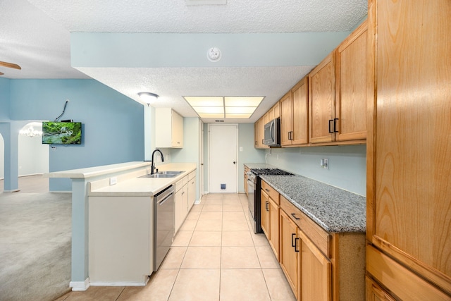 19302 Peach Valley Cir, Houston, TX 77084 - kitchen with stainless steel appliances, a sink, a peninsula, a textured ceiling, and light tile patterned floors