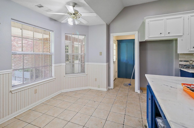 kitchen featuring light tile patterned floors, visible vents, white cabinetry, a wainscoted wall, and light countertops