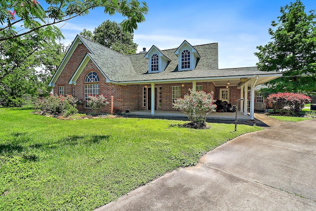 view of front of property with a front yard, a shingled roof, brick siding, and covered porch