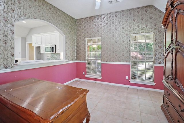 interior space with a wainscoted wall, lofted ceiling, a ceiling fan, and wallpapered walls