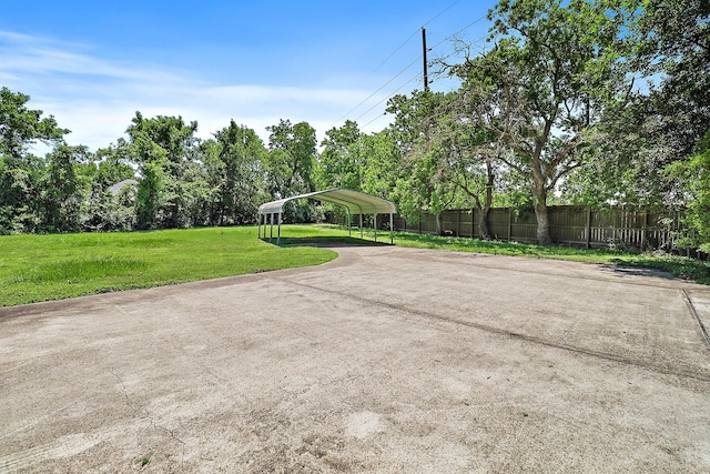 view of patio with concrete driveway, a detached carport, and fence