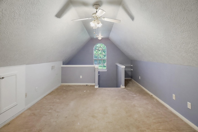 additional living space featuring lofted ceiling, carpet floors, baseboards, and a textured ceiling