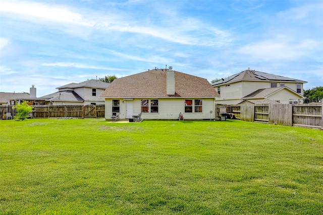 rear view of property with a lawn, a fenced backyard, and a chimney