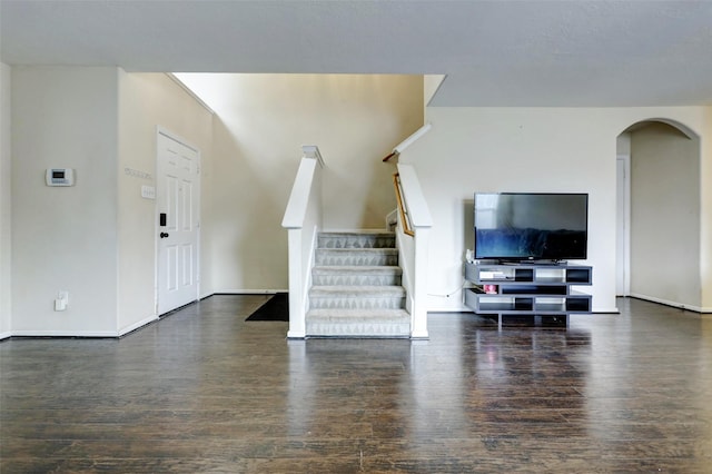 living area with baseboards, arched walkways, stairs, and wood finished floors