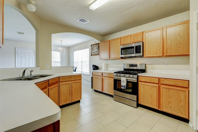 kitchen featuring light countertops, a sink, arched walkways, and stainless steel appliances