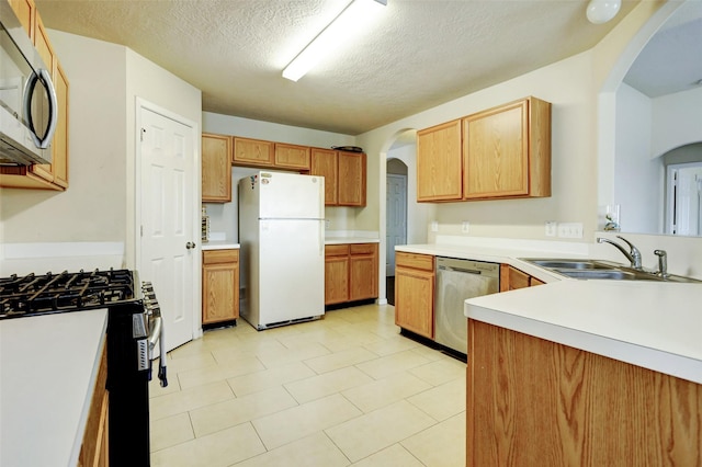 kitchen featuring light countertops, stainless steel appliances, arched walkways, and a sink