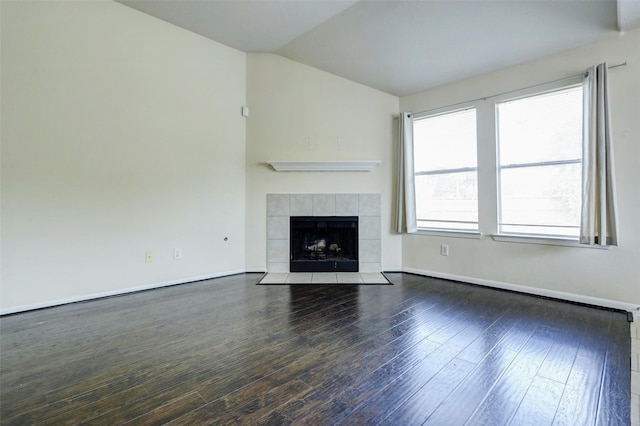 unfurnished living room with baseboards, a fireplace, wood finished floors, and lofted ceiling