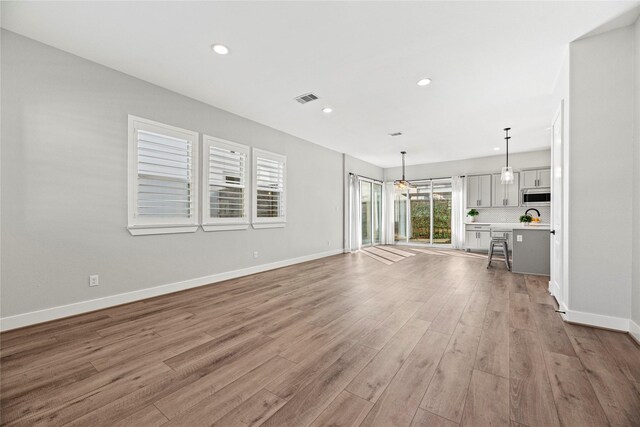 unfurnished living room featuring recessed lighting, wood finished floors, visible vents, and baseboards