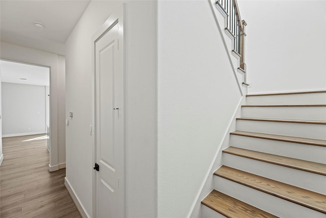 staircase featuring wood finished floors and baseboards