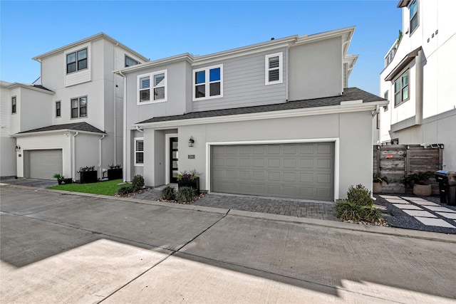 view of front of property with an attached garage, fence, stucco siding, and driveway
