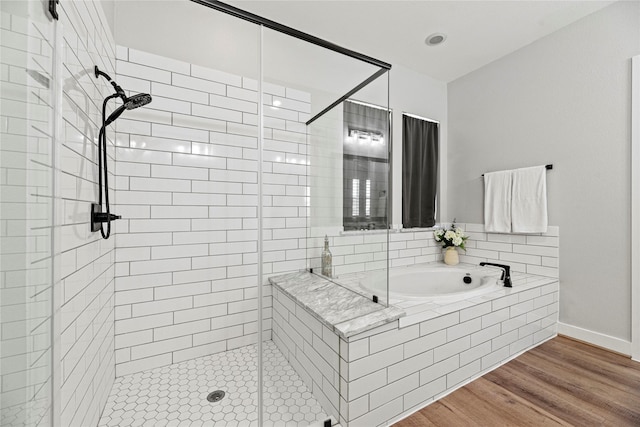 full bath with baseboards, a garden tub, wood finished floors, and a shower stall