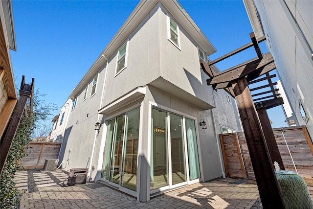 rear view of house with stucco siding, fence, and a patio area