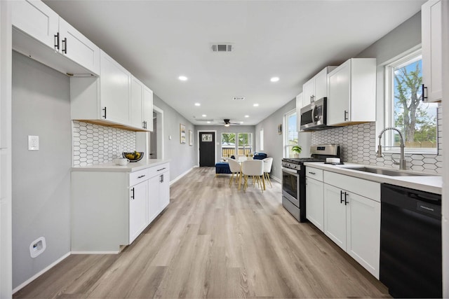 6810 Cohn St, Houston, TX 77091 - kitchen with baseboards, a sink, light wood-style floors, and appliances with stainless steel finishes