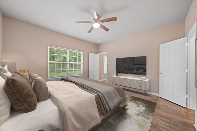 bedroom with ceiling fan, wood finished floors, and baseboards