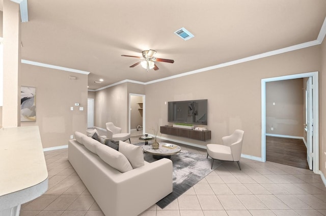 living area with light tile patterned flooring, crown molding, a ceiling fan, visible vents, and baseboards