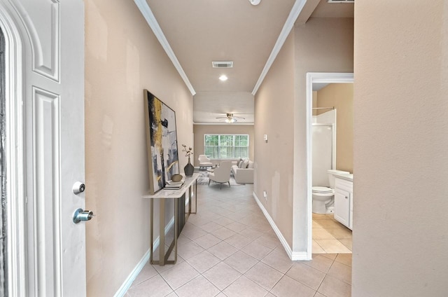 hallway with baseboards, visible vents, ornamental molding, and light tile patterned floors