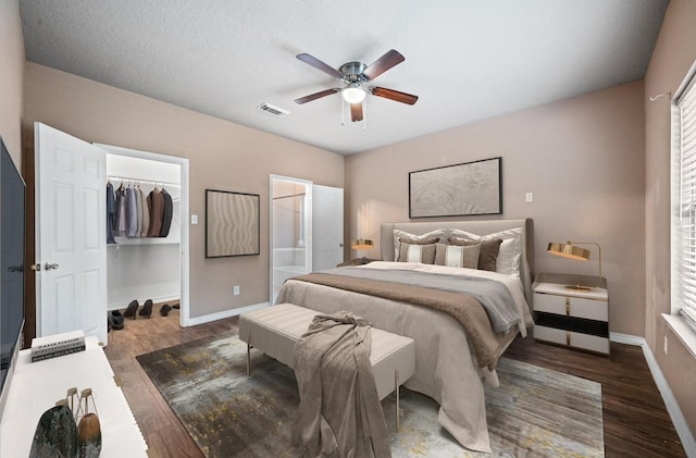 bedroom featuring visible vents, a closet, baseboards, wood finished floors, and a spacious closet