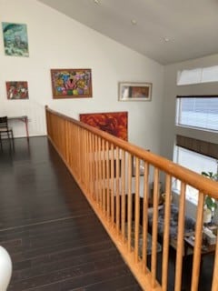 hallway with vaulted ceiling, wood finished floors, and an upstairs landing